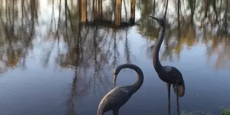Outdoor wedding venue featuring a pond, wooden gazebo, and decorative bird sculptures.