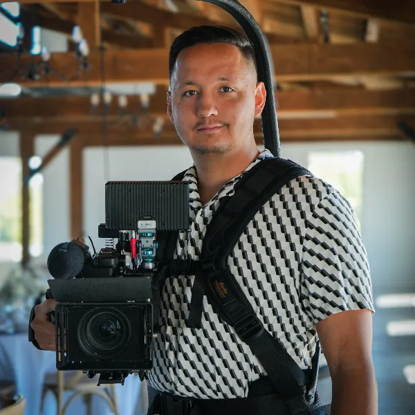 Kyle Andersen holding a professional cinema camera rig in a wedding venue