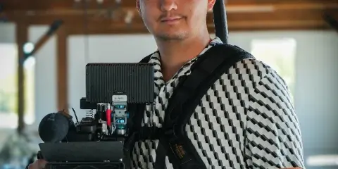 Kyle Andersen holding a professional cinema camera rig in a wedding venue