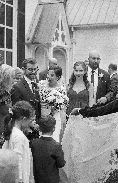 Black and white photograph of a bride and groom with their wedding party standing outside a church.
