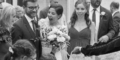 Black and white photograph of a bride and groom with their wedding party standing outside a church.