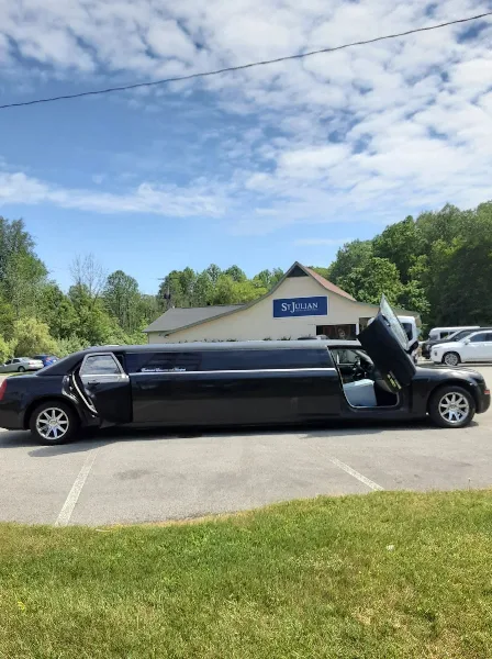 A black stretch limousine with company branding parked in a lot with a building in the background.