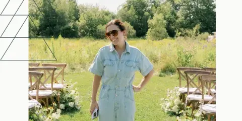 A woman in denim overalls standing in a grassy wedding aisle with chairs and flowers.