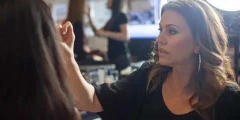 A professional hair and makeup artist working on a client's hair in a salon.