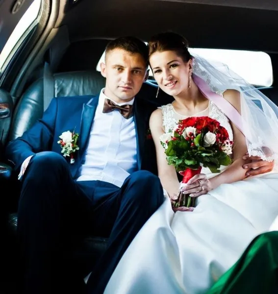 A bride and groom seated in the back of a limousine.