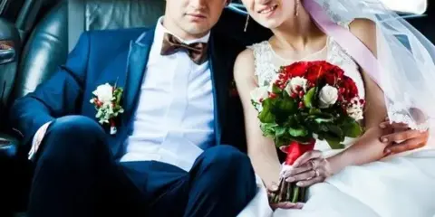 A bride and groom seated in the back of a limousine.