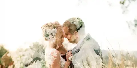 A bride and groom embracing in a field with floral details