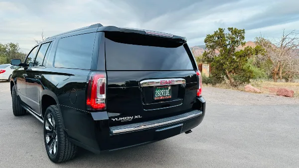 Rear view of a black GMC Yukon XL SUV with a custom '282RIDE' license plate, parked outdoors in a desert landscape.