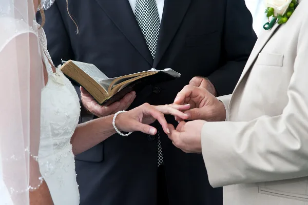 Close-up of a bride and groom exchanging rings during a wedding ceremony.