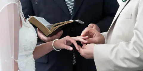 Close-up of a bride and groom exchanging rings during a wedding ceremony.