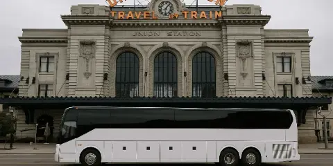 A white luxury charter bus parked in front of a building.