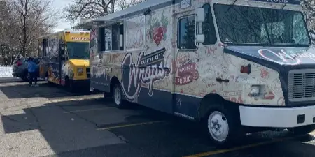 A white and blue mobile food truck branded with 'Capital City Wraps' parked in a lot.
