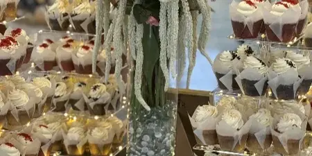 A tiered stand filled with assorted cupcakes and a floral centerpiece at a wedding event.