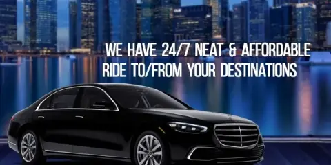 Black luxury sedan parked in front of a city skyline at dusk
