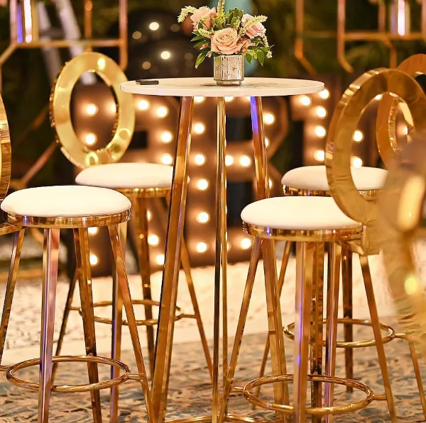 Gold bar stools and a high-top table set up for an event with floral centerpiece