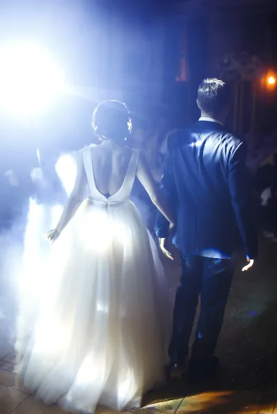 Bride and groom dancing at a wedding reception under bright stage lights.