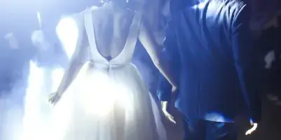 Bride and groom dancing at a wedding reception under bright stage lights.