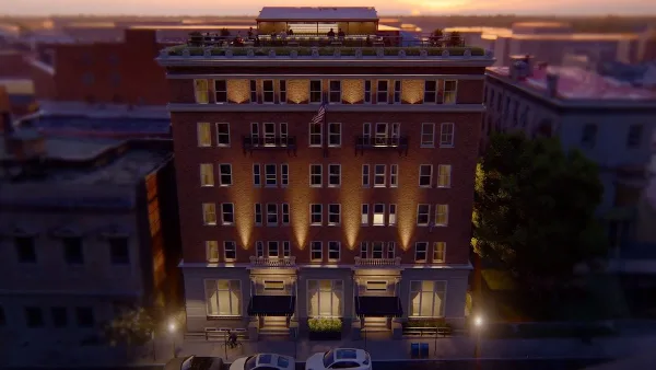 Exterior view of the Hotel Petersburg, a historic brick building with a rooftop terrace, at dusk.