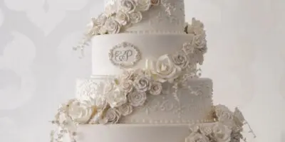 A five-tier white wedding cake decorated with cascading sugar roses and lace details.