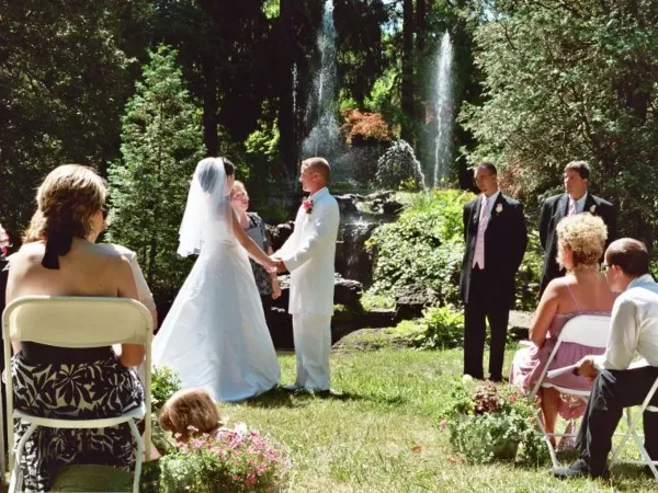 A bride and groom exchanging vows during an outdoor wedding ceremony in a garden setting.