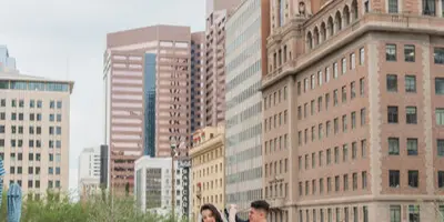 A bride and groom standing on a rooftop terrace with a city skyline in the background.