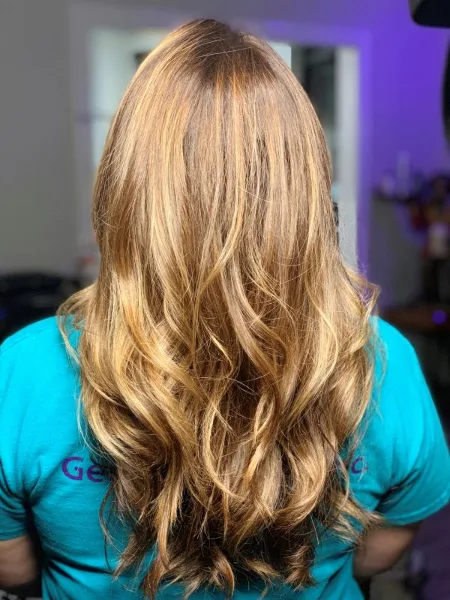 Back view of a client with long, wavy blonde hair showing a styled and colored finish.