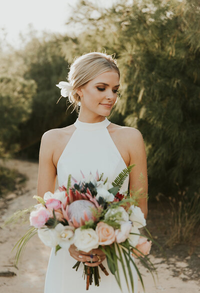 Bride with styled updo and makeup holding a bouquet