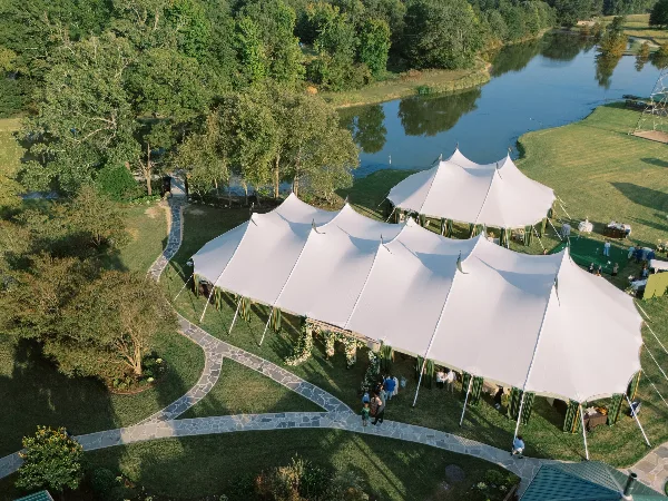 White sailcloth event tents beside a pond