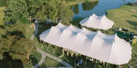 White sailcloth event tents beside a pond