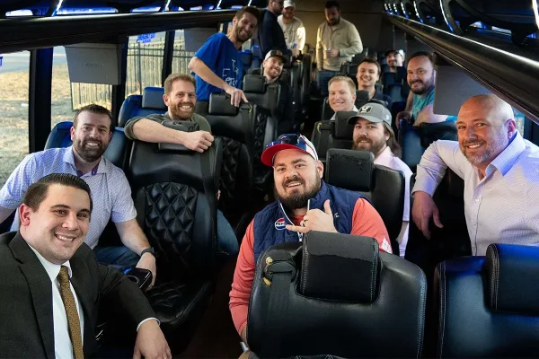 A group of smiling passengers seated inside a luxury shuttle bus.