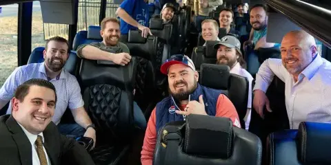 A group of smiling passengers seated inside a luxury shuttle bus.