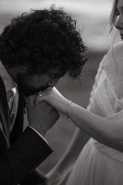 Black and white photo of a groom kissing a bride's hand