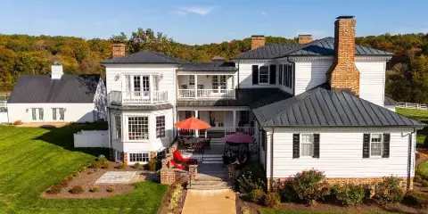 Aerial view of a large white wedding venue estate with a patio and green lawns.