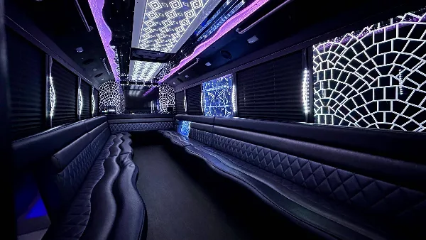 Interior view of a luxury party bus featuring black leather bench seating, purple ambient lighting, and decorative window panels.