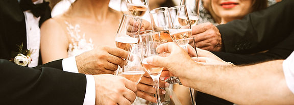 A group of people at a wedding raising champagne flutes in a toast.