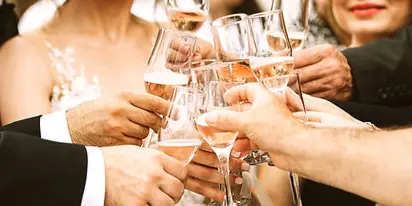 A group of people at a wedding raising champagne flutes in a toast.