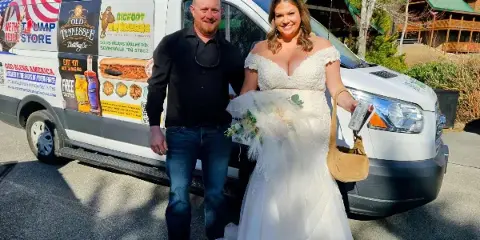 A bride and groom posing in front of a white passenger van.