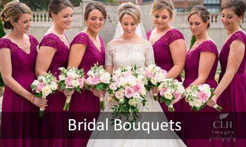 A bride and bridesmaids in purple dresses holding pink and white floral bouquets.