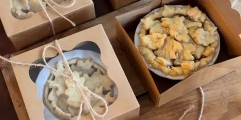 Rustic cardboard boxes containing pies and cookies, tied with twine, arranged on a wooden table.