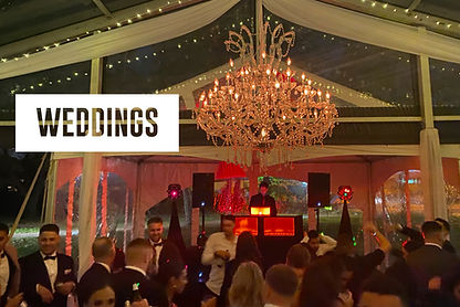 Wedding reception with a DJ at a booth, chandelier lighting, and guests dancing on the floor.