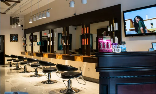 Interior of a hair salon with black styling chairs, mirrors, and shelves of hair products.