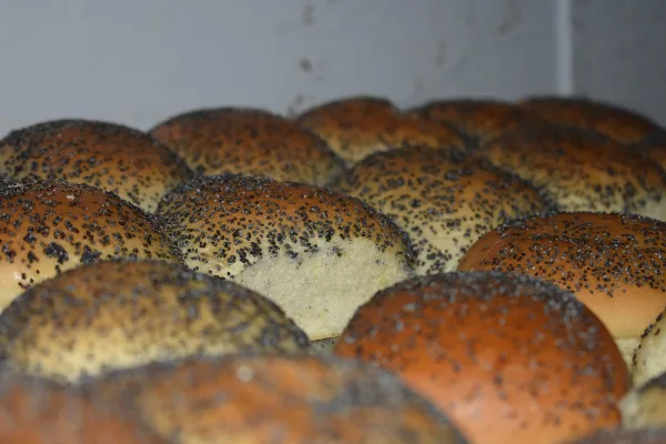 Close-up of golden-brown baked bread rolls topped with poppy seeds.