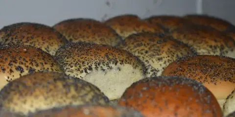Close-up of golden-brown baked bread rolls topped with poppy seeds.