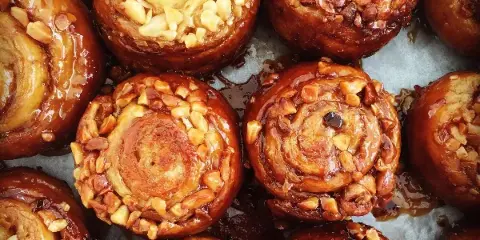 Close-up of glazed baked pastries topped with chopped nuts