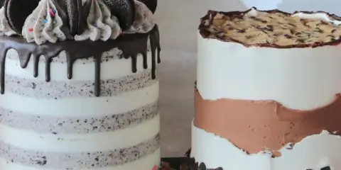 Two decorated cakes, one with chocolate drip and Oreo toppings, and another with a semi-naked style and chocolate chunks, displayed on a table.