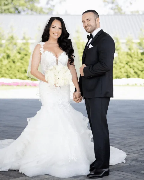A groom in a black tuxedo and bow tie standing next to a bride in a white wedding dress.