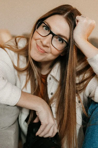 Portrait of a woman with glasses and long hair holding a camera