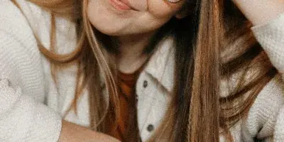 Portrait of a woman with glasses and long hair holding a camera