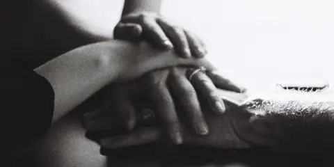 Black-and-white close-up of multiple hands stacked together, one wearing a ring.