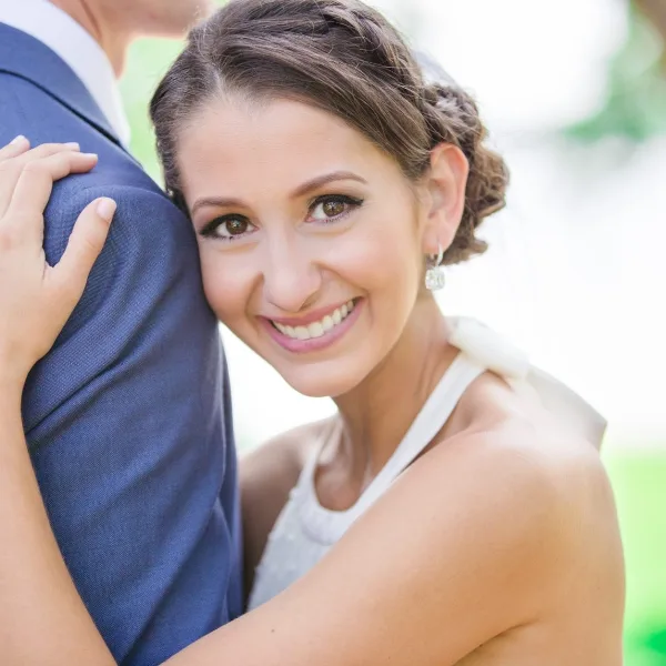 Bride in a white dress smiling while embracing a groom in a blue suit